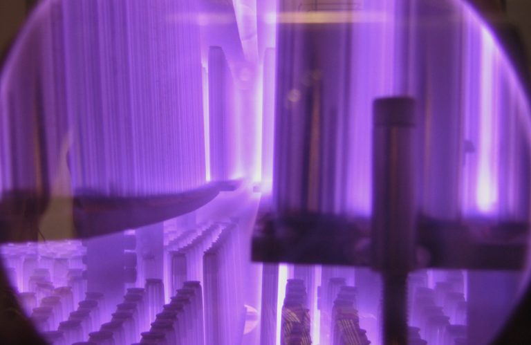 Lila Lichtstrahlen und geometrische Formen vor einem dunklen Hintergrund.